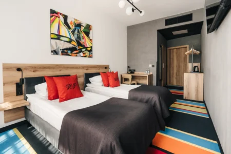 Pokój hotelowy z kolorowym dywanem i czerwonymi dodatkami